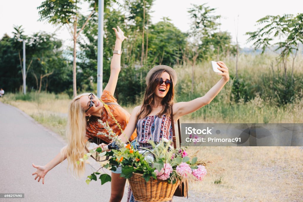 Girl friends are taking selfie on a bike Two girls taking selfie on a beautiful day Flower Stock Photo