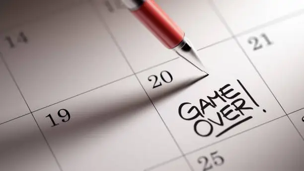 Closeup of a personal agenda setting an important date written with pen. The words Game over written on a white notebook to remind you an important appointment.