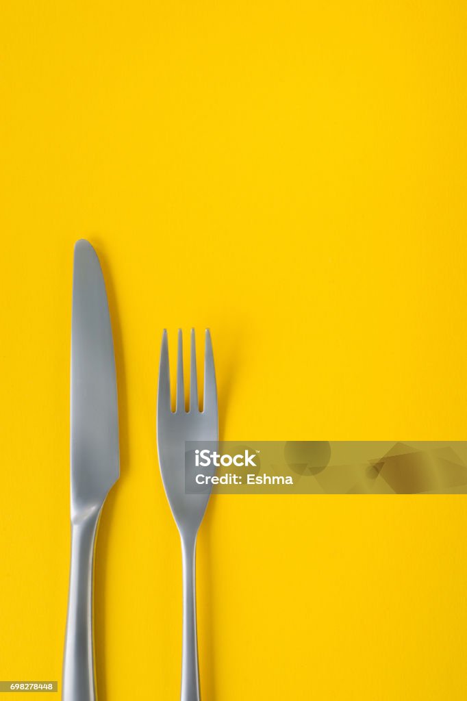 Fourchette et couteau sur fond jaune, composition clairsemée avec espace de copie. - Photo de Table dressée libre de droits