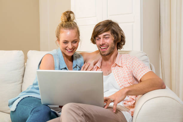 istock Cute couple using laptop sitting on the couch 698307688