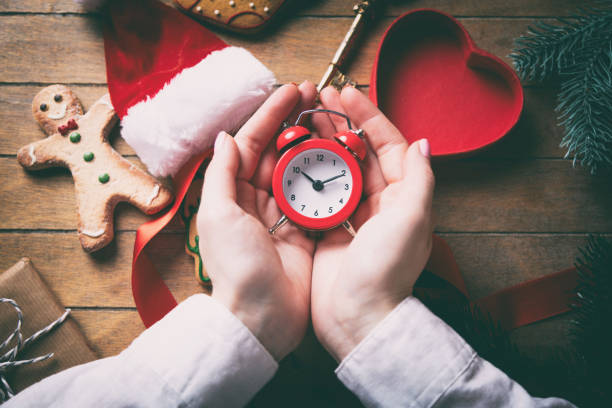 istock hands wrapping christmas alarm clock and gifts 698327238