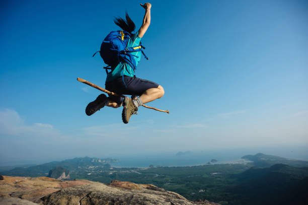 cheering woman jumping on rocky mountain top - witchcraft heights imagens e fotografias de stock