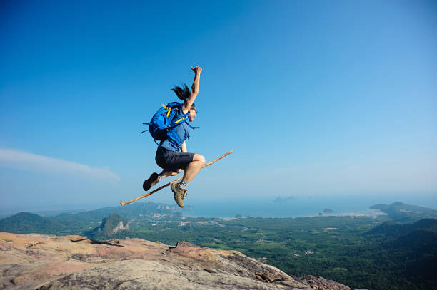 istock cheering woman jumping on rocky mountain top 698336768
