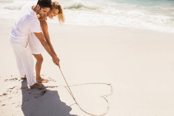 istock Couple drawing heart on sand 698338600