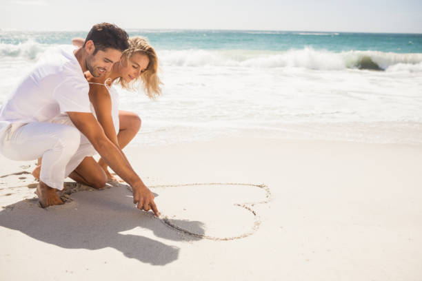 istock Couple drawing heart on sand 698338706