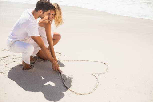 istock Couple drawing heart on sand 698338744