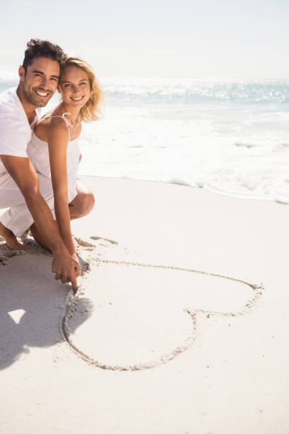 istock Couple drawing heart on sand 698338770