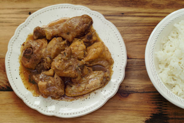 istock boiled chicken with sauce in white plate and rice in bowl on brown background 698348514