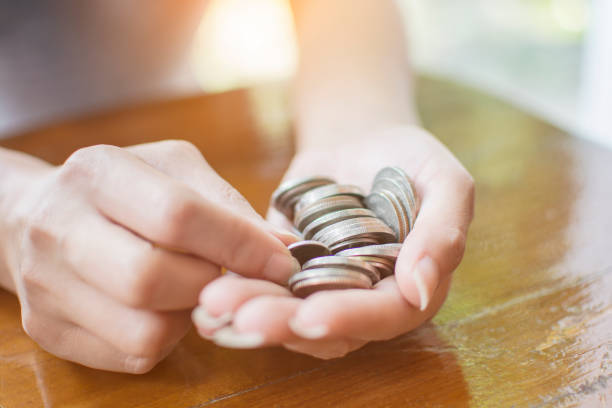 Close up hand of the woman hold coins and pile coin for saving. money saving concept Close up hand of the woman hold coins and pile coin for saving. money saving concept counting coins stock pictures, royalty-free photos & images