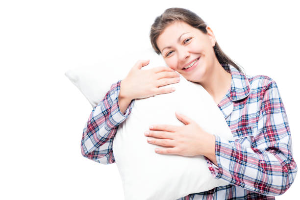 istock Happy brunette in pajama hugs soft pillow against white background 698356724