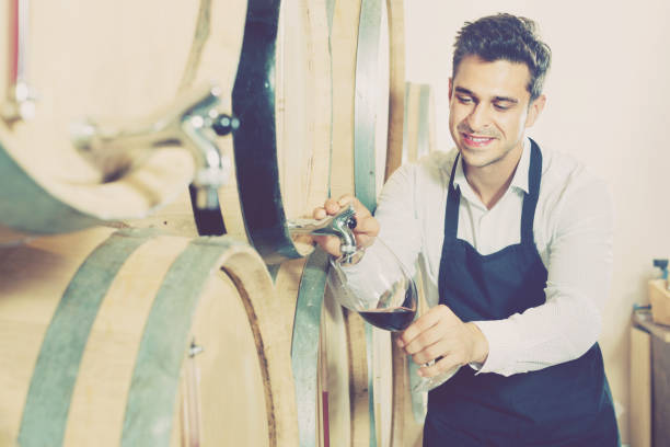 istock Man pouring red wine into glass in alcohol section 698366732
