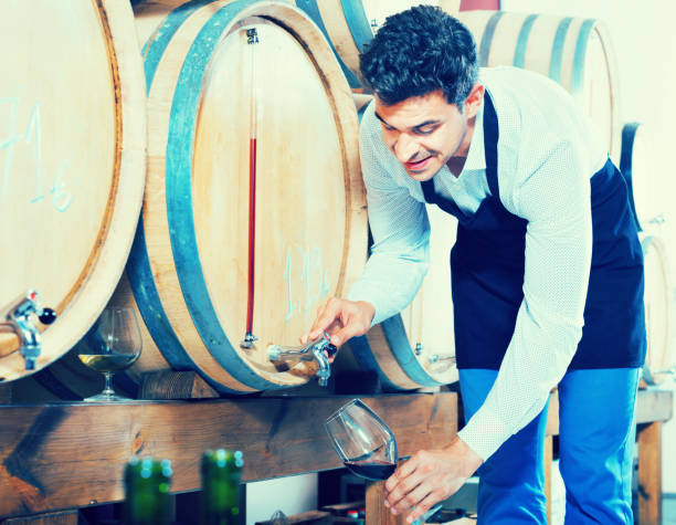 istock Man pouring red wine into glass in alcohol section 698366738