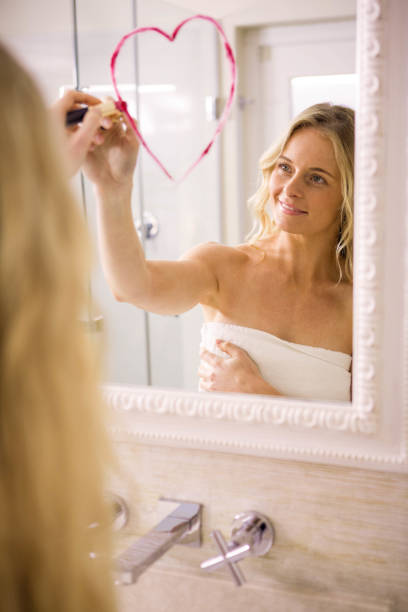 istock Beautiful blonde drawing big heart on mirror 698378008