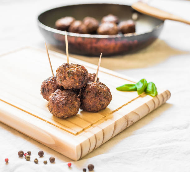 istock Meatballs on a wooden board with toothpicks against white background 698414708