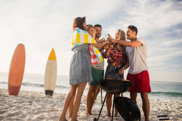 Happy friends having fun around barbecue Happy friends having fun around barbecue on the beach south african braai stock pictures, royalty-free photos & images