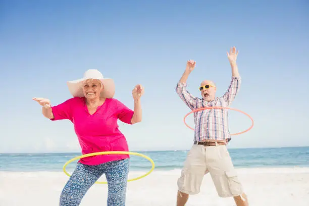 Senior couple doing hula hoop on the beach