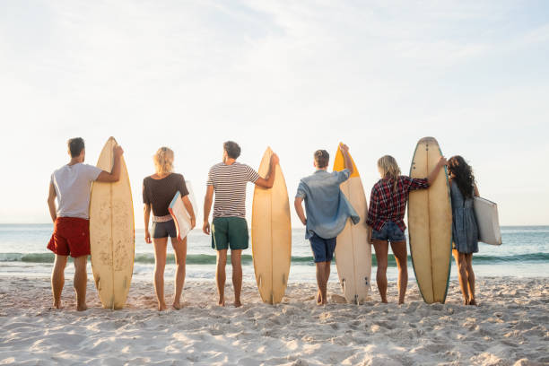 istock Happy friends standing in line with surfboards 698476016