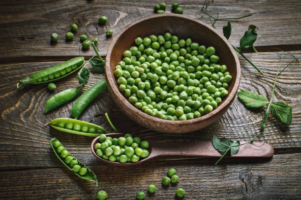 istock Delicious ripe green peas lying on a wooden table 698499754