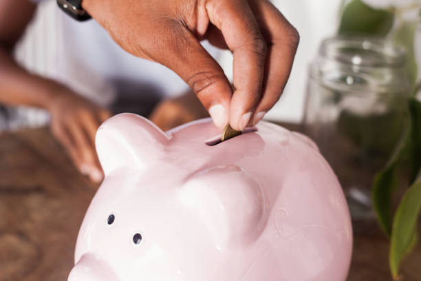 istock Man dropping a coin into piggy bank. 698500696