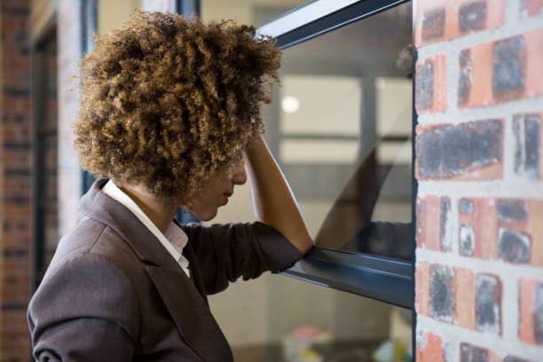 istock Tired businesswoman leaning on window 698501730