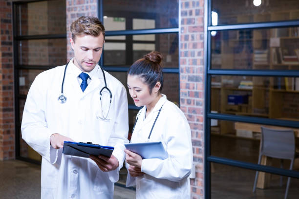 istock Two doctors looking at clipboard and discussing near library 698502094