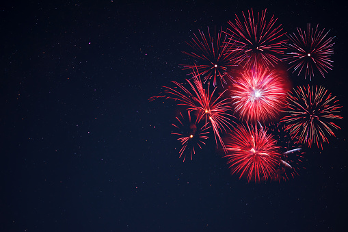 Amazing red celebration fireworks located right side over night sky, copy space.  Independence Day, 4th of July, New Year holidays salute background.