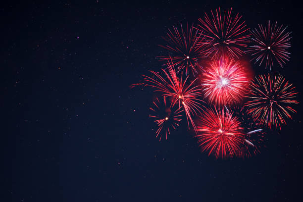 Red  fireworks located right side over night sky Amazing red celebration fireworks located right side over night sky, copy space.  Independence Day, 4th of July, New Year holidays salute background. independence day holiday photos stock pictures, royalty-free photos & images