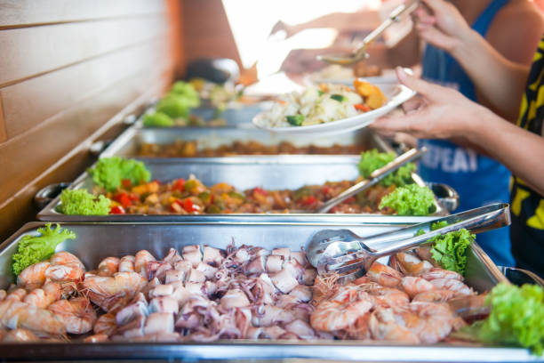 A cropped image captures business people using service tongs to carefully select their food from the buffet line, showcasing a refined and organized dining experience.