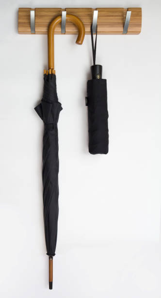 istock Two black men's umbrellas hang on hook rack, white background 698545784