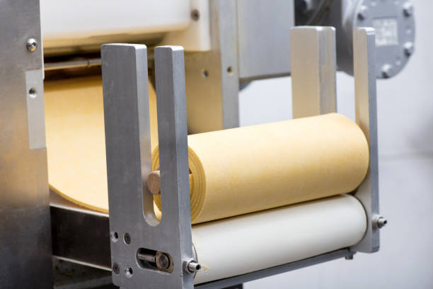 istock Roll of uncooked pasta dough on a machine 698552836