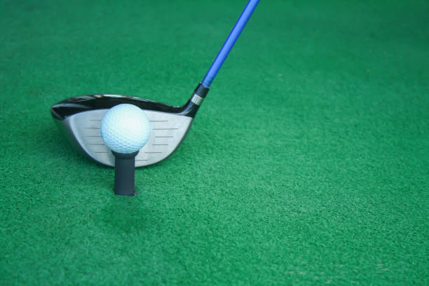 istock golf ball on tee with driver club, in front of driver, driving range 698563990