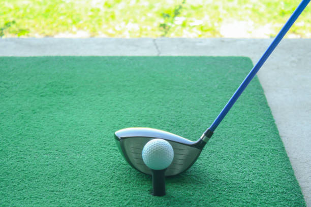 istock golf ball on tee with driver club, in front of driver, driving range 698564068