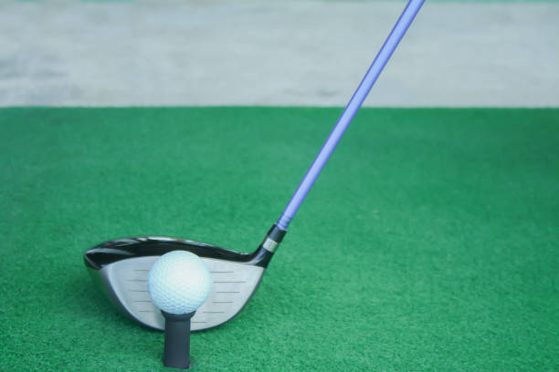 istock golf ball on tee with driver club, in front of driver, driving range 698564098