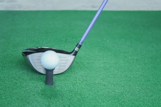 istock golf ball on tee with driver club, in front of driver, driving range 698564154