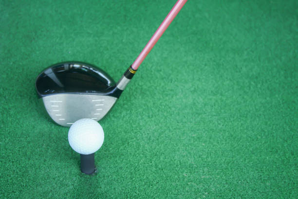 istock golf ball on tee with driver club, in front of driver, driving range 698564238