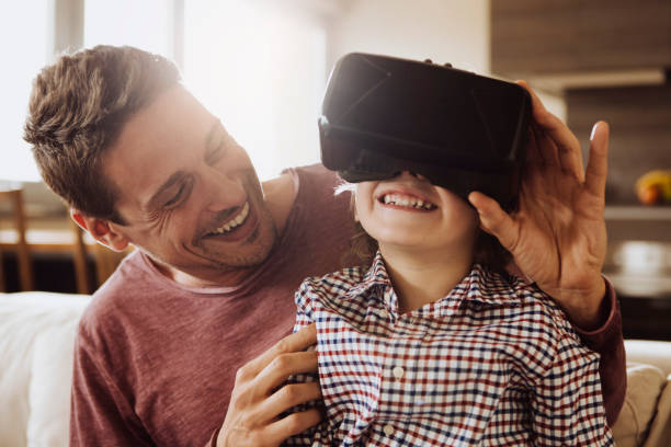 Father and son having a fun Father and son having a fun at home with VR. head mounted display stock pictures, royalty-free photos & images