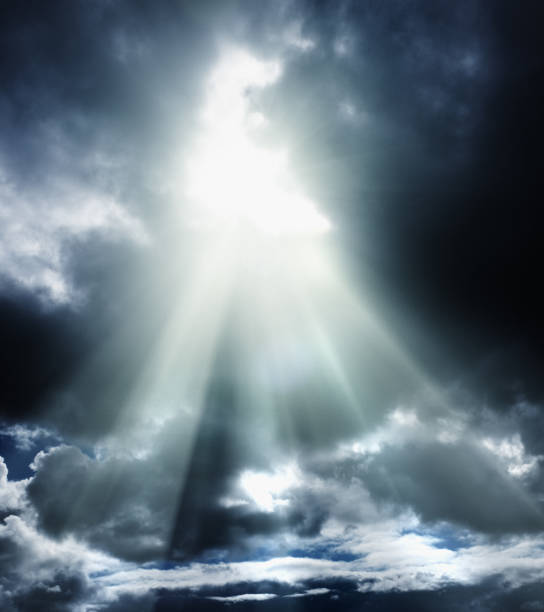 From a dark, brooding, clouded sky, a break in the clouds allows brilliant rays of sunshine to shine through, looking like a message from Heaven.