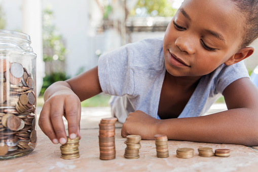 Young african female counting her coins while lying on the floor.