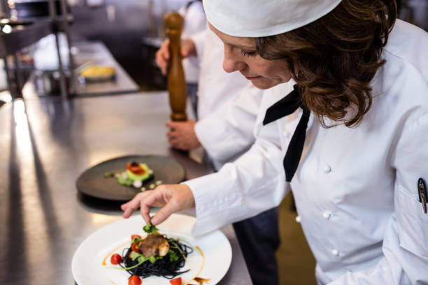 istock Female chef garnishing meal on counter 698591576