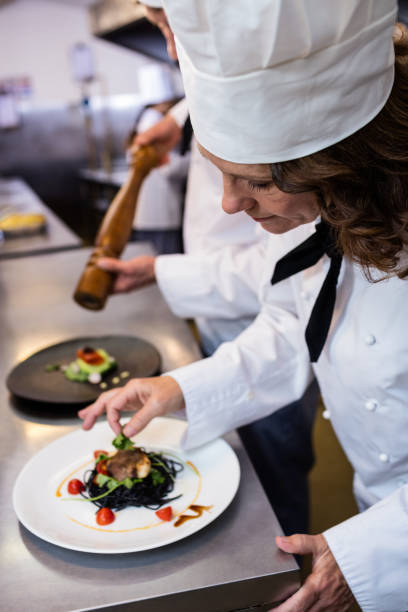 istock Female chef garnishing meal on counter 698591678
