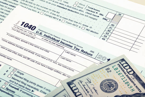 istock US 1040 Tax Form and dollars - studio shot. Filtered image: cross processed vintage effect. 698594082