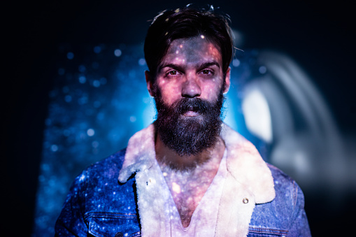 Stars and sky image projected on a bearded man's upper boddy.