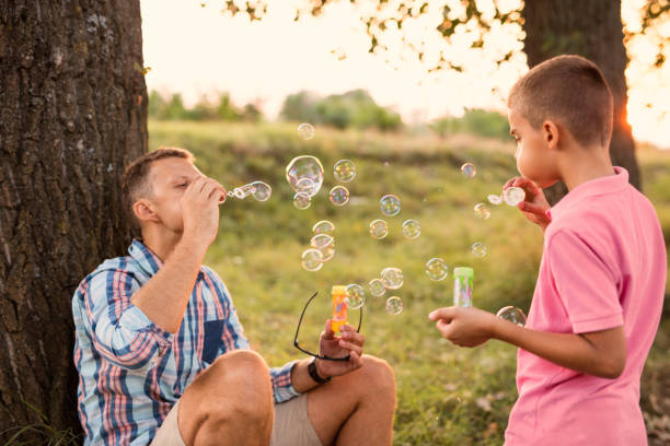 istock Boy blowing soap bubbles with his daddy. Family concept 698602248
