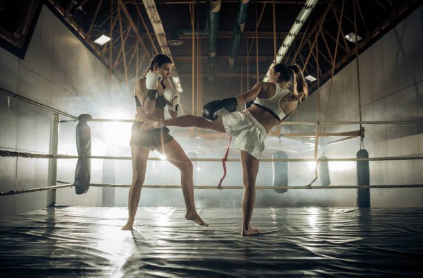 volle länge des sportlichen frauen kämpfen auf einem kickbox-match in einem fitnessstudio. - muay thai stock-fotos und bilder