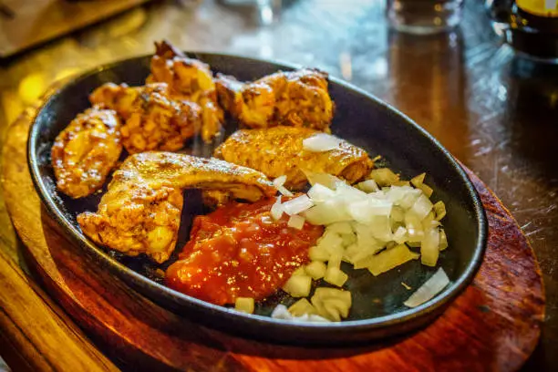 Chicken wings, onions and tomato salsa on sizzler dish