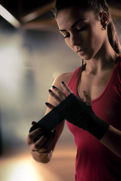 istock Young female boxer wrapping her hands before a sports training. 698610116
