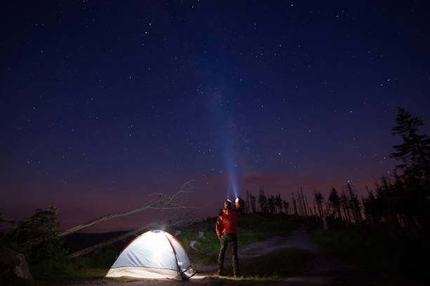 istock Man tourist pointing his flashlight to the starry sky 698610662