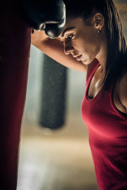 istock Exhausted female boxer taking a rest from exercising in a gym. 698613952