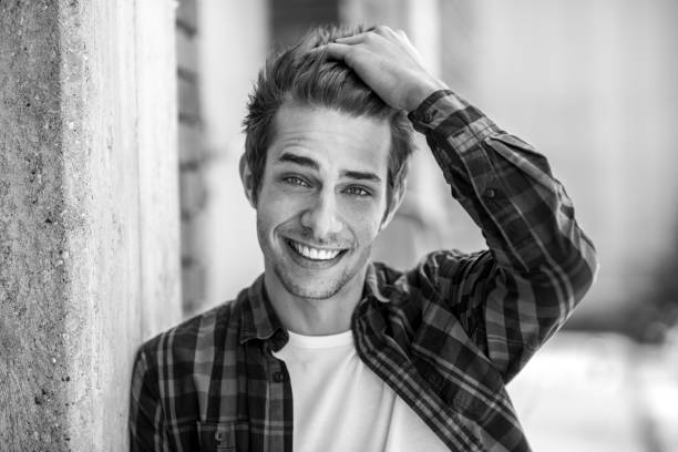 istock smiling young man leaning at brick wall 698615108