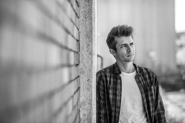 istock pensive young man leaning at brick wall 698615258